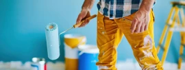 Painter holding a paint roller with paint cans and tools during an interior painting project
