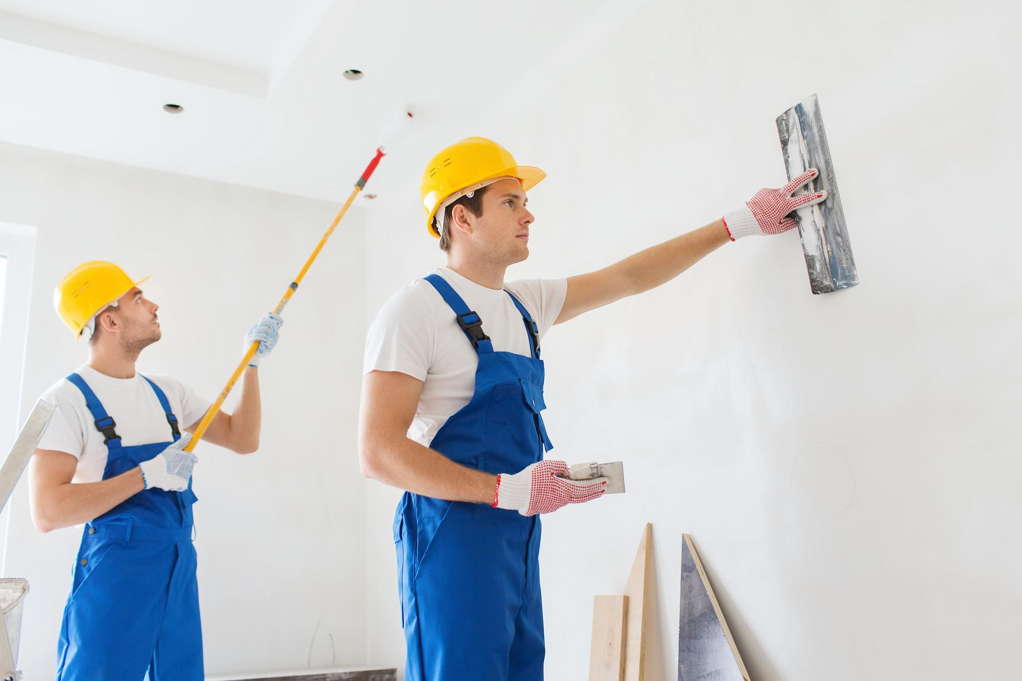 Professional painters smoothing and painting interior walls during a home renovation